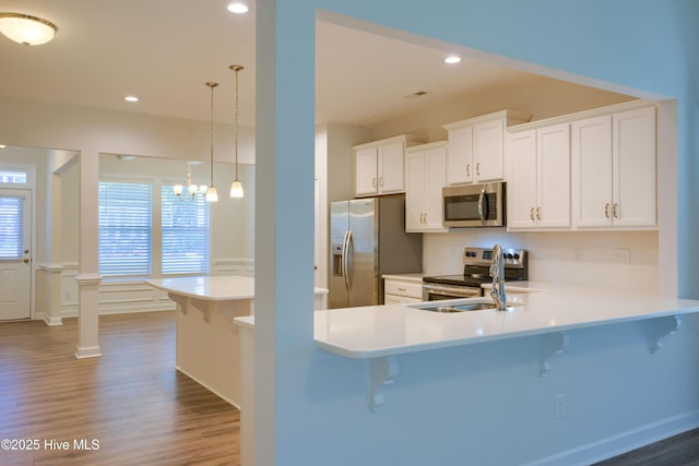 kitchen with light countertops, appliances with stainless steel finishes, a peninsula, and pendant lighting