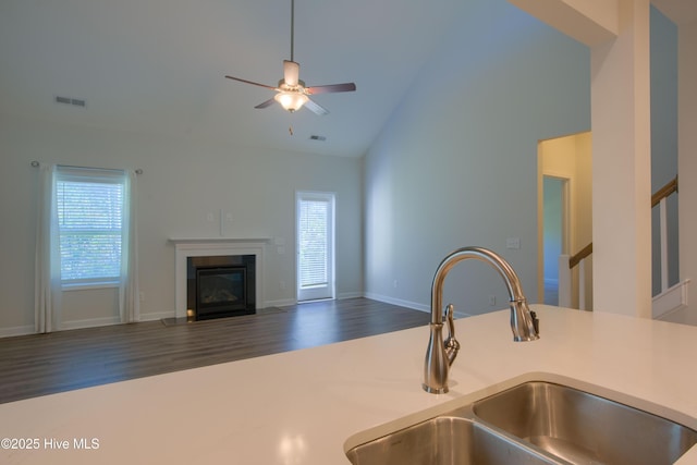 kitchen with visible vents, a fireplace with flush hearth, open floor plan, light countertops, and a sink