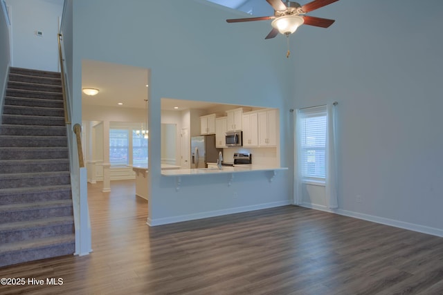 kitchen featuring white cabinets, appliances with stainless steel finishes, a peninsula, light countertops, and a kitchen bar