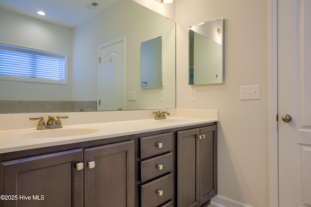 full bath with double vanity, visible vents, and a sink