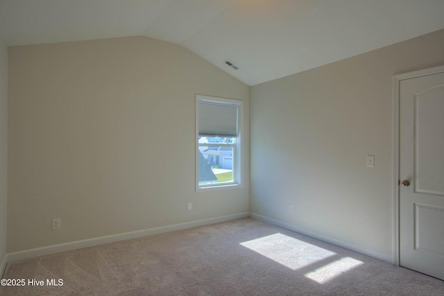 unfurnished room featuring light colored carpet, visible vents, vaulted ceiling, and baseboards