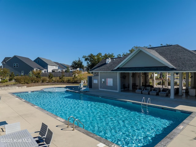 pool with a residential view, fence, and a patio