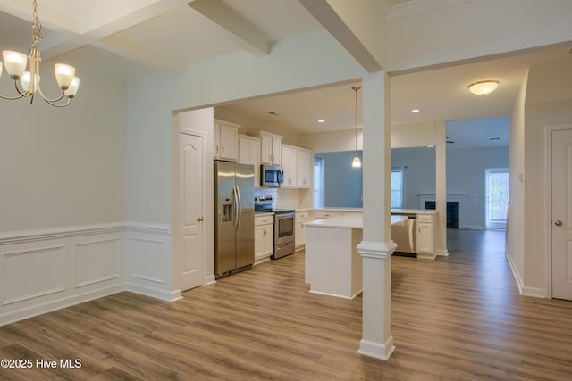 kitchen with a peninsula, white cabinets, light countertops, appliances with stainless steel finishes, and decorative light fixtures