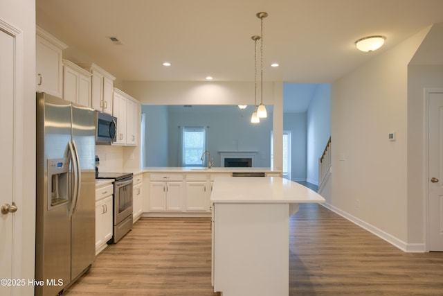 kitchen featuring stainless steel appliances, light countertops, a peninsula, and white cabinetry