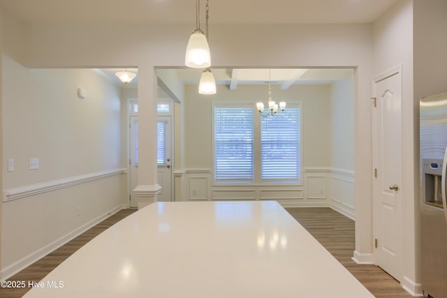 kitchen featuring beam ceiling, pendant lighting, dark wood-style flooring, light countertops, and stainless steel fridge