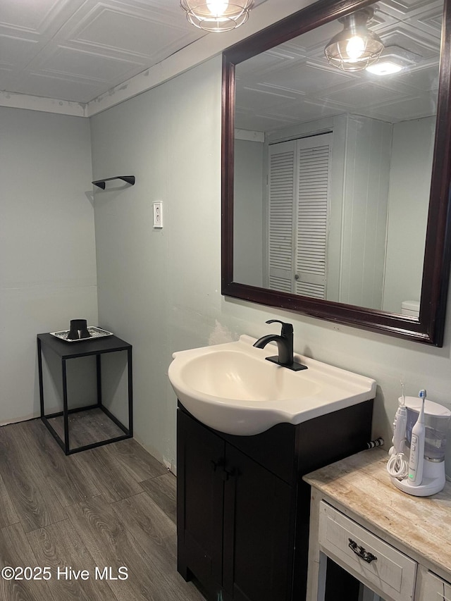 bathroom with a closet, wood finished floors, and vanity