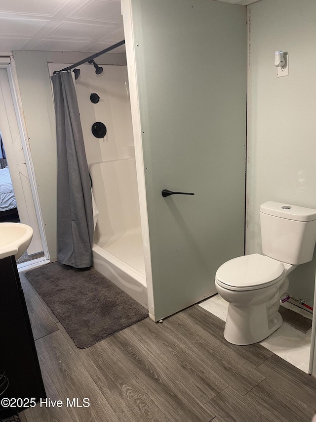 full bathroom featuring toilet, a shower stall, wood finished floors, and vanity