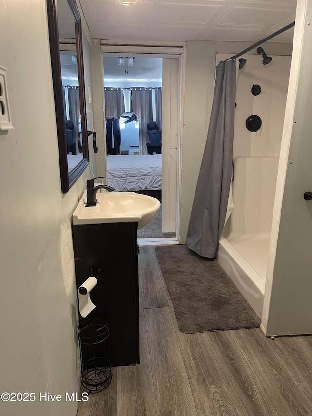 full bathroom featuring a stall shower, ensuite bath, wood finished floors, and vanity