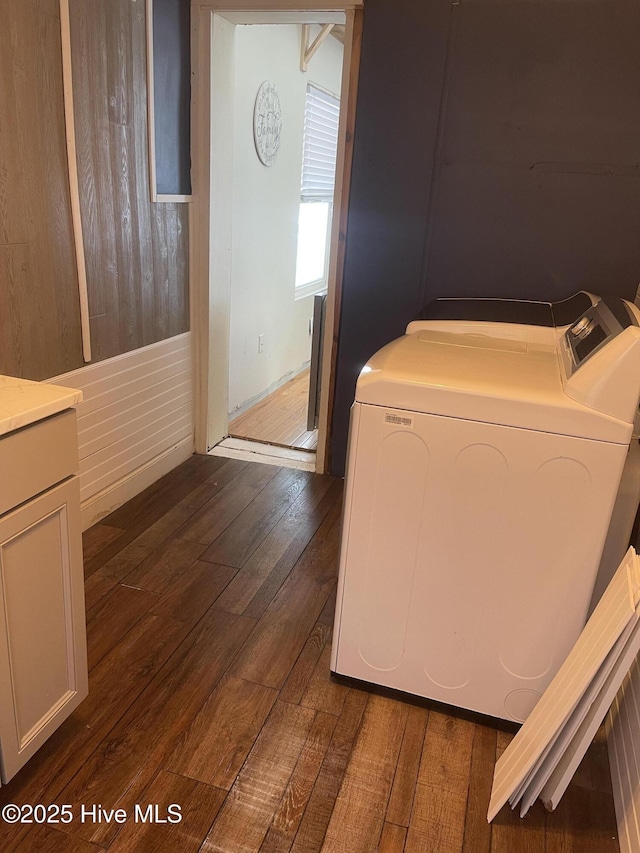 clothes washing area with dark wood-style floors, laundry area, and washer and clothes dryer