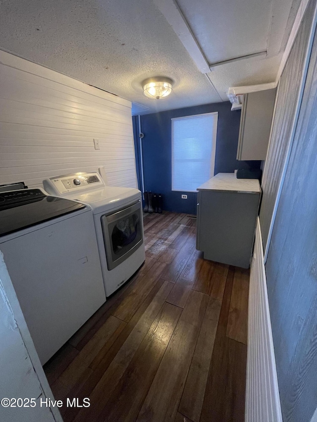 washroom featuring a textured ceiling, wooden walls, laundry area, dark wood-type flooring, and washer and clothes dryer