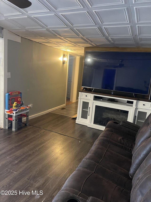 living area with an ornate ceiling, baseboards, and dark wood-style flooring