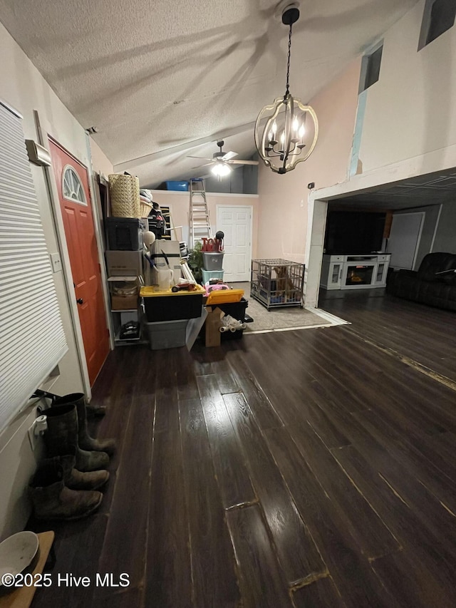 interior space featuring vaulted ceiling, a textured ceiling, ceiling fan with notable chandelier, and wood finished floors