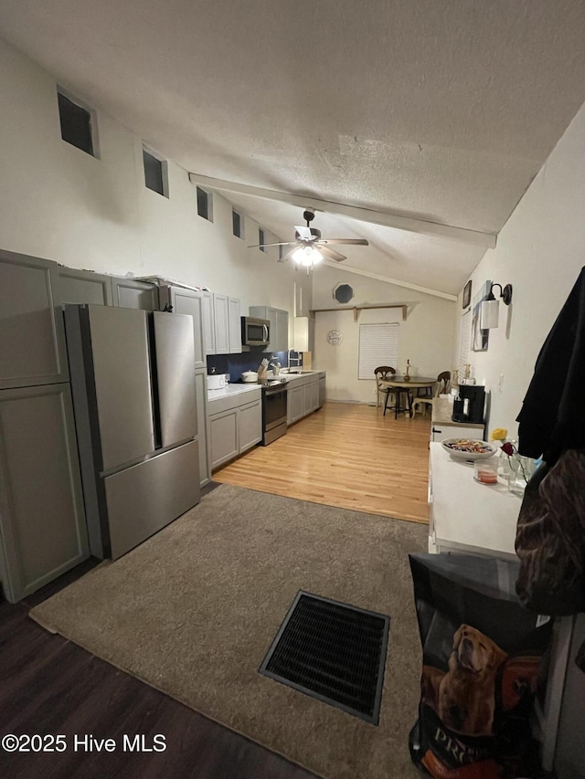 kitchen featuring lofted ceiling, stainless steel appliances, and gray cabinetry