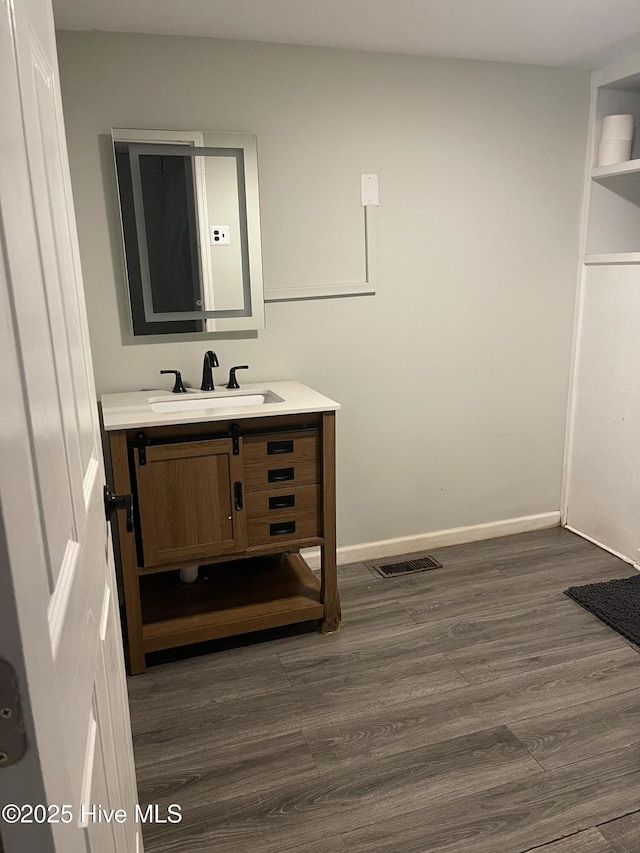 bathroom featuring visible vents, wood finished floors, vanity, and baseboards