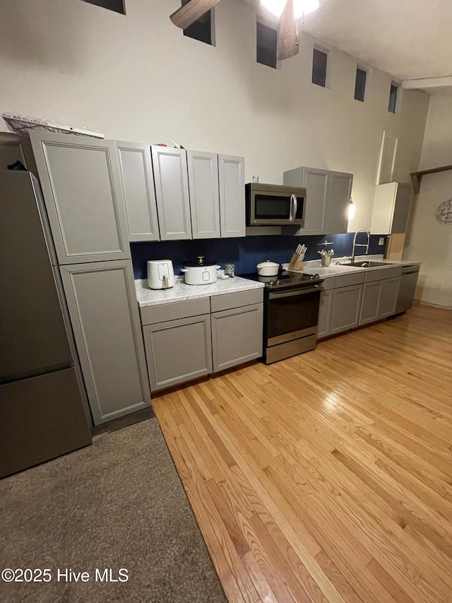 kitchen featuring appliances with stainless steel finishes, gray cabinets, and a sink