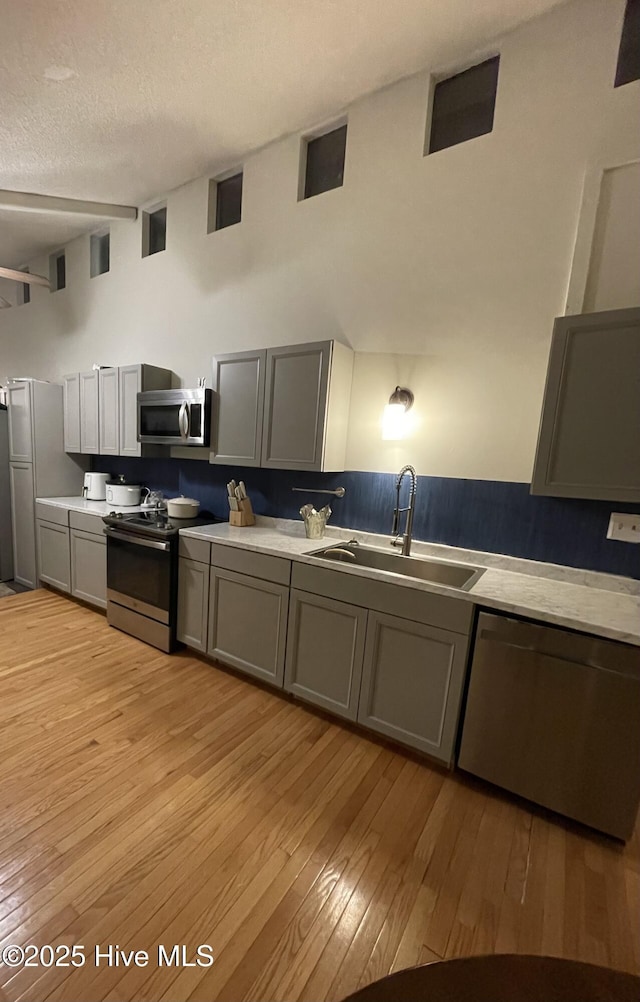 kitchen featuring a sink, stainless steel appliances, light countertops, and gray cabinetry