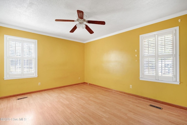 spare room with a textured ceiling, wood finished floors, visible vents, and baseboards