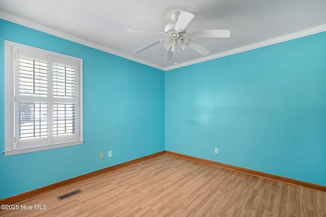 empty room featuring baseboards, light wood-style flooring, visible vents, and crown molding