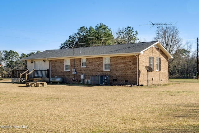 rear view of house with cooling unit, crawl space, brick siding, and a yard