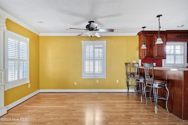 kitchen featuring ornamental molding, light countertops, hanging light fixtures, and light wood-style flooring