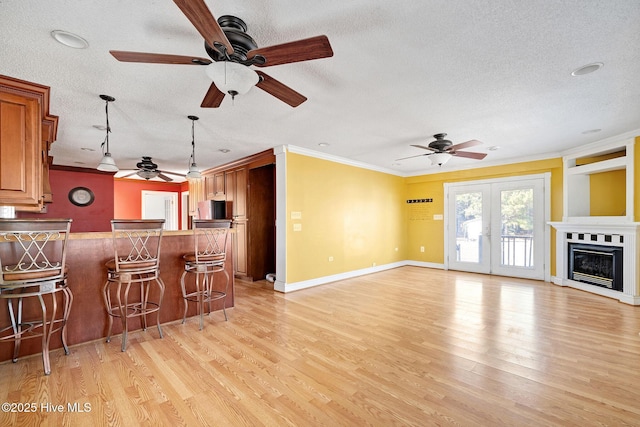 kitchen with brown cabinetry, a breakfast bar, open floor plan, hanging light fixtures, and light wood-type flooring