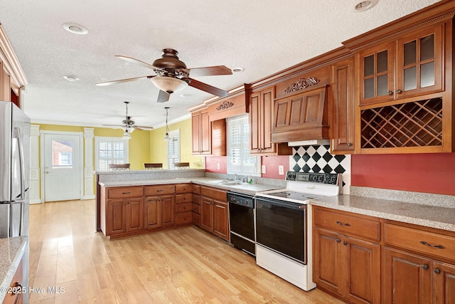 kitchen featuring pendant lighting, brown cabinets, freestanding refrigerator, range with electric cooktop, and dishwasher