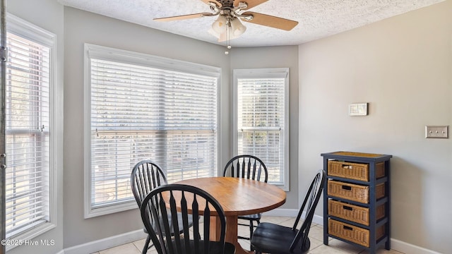 dining room with a healthy amount of sunlight, light tile patterned floors, a ceiling fan, and a textured ceiling