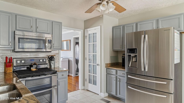kitchen with visible vents, gray cabinets, stainless steel appliances, a textured ceiling, and light tile patterned flooring