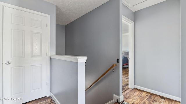 staircase with a textured ceiling, baseboards, and wood finished floors