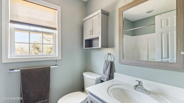 bathroom featuring toilet, walk in shower, and vanity