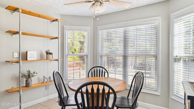 dining area featuring a ceiling fan, a textured ceiling, baseboards, and light tile patterned floors