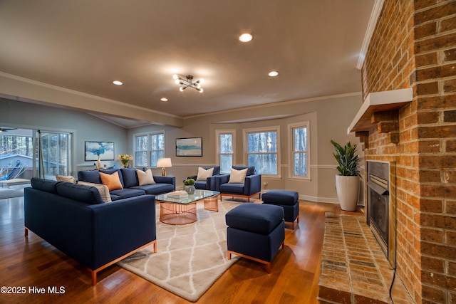 living area with baseboards, wood finished floors, crown molding, a fireplace, and recessed lighting