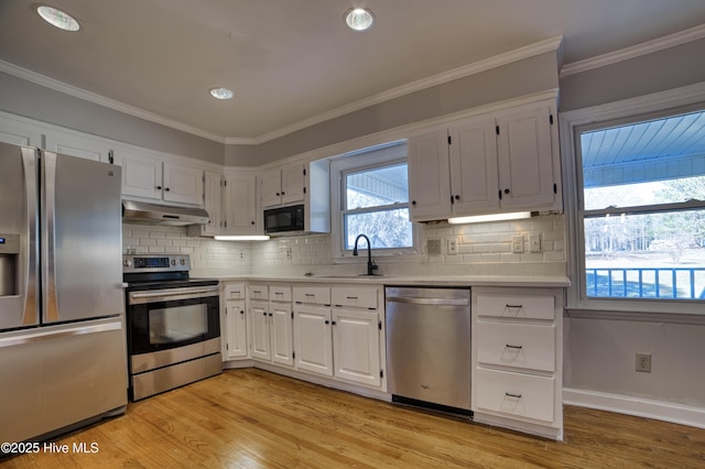 kitchen featuring stainless steel appliances, light countertops, white cabinetry, a sink, and under cabinet range hood