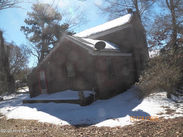 view of snowy exterior featuring brick siding