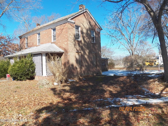 view of side of property featuring a chimney and brick siding