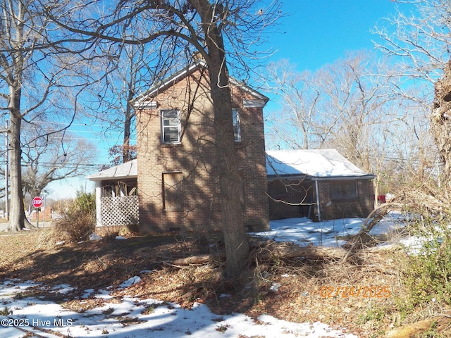 view of snowy exterior featuring brick siding