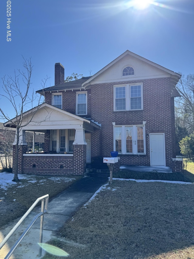 view of front of property featuring covered porch, a chimney, and brick siding