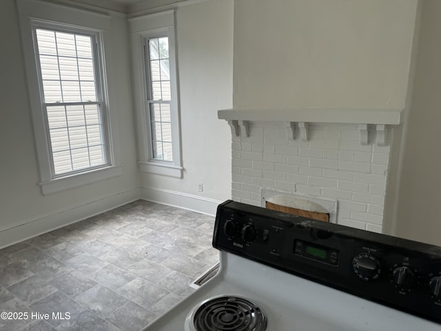 kitchen featuring a healthy amount of sunlight, electric range, baseboards, and light countertops