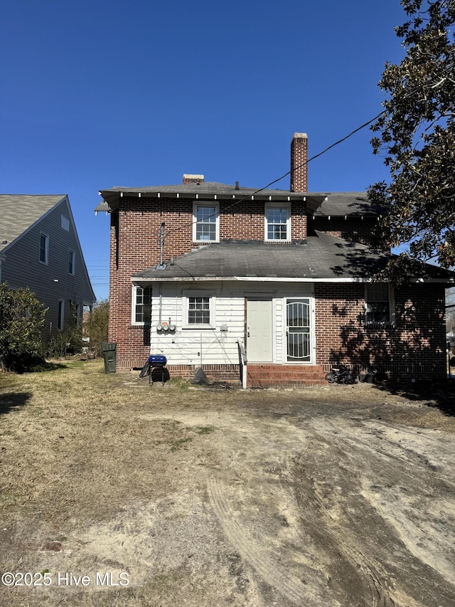 back of property featuring brick siding and a chimney