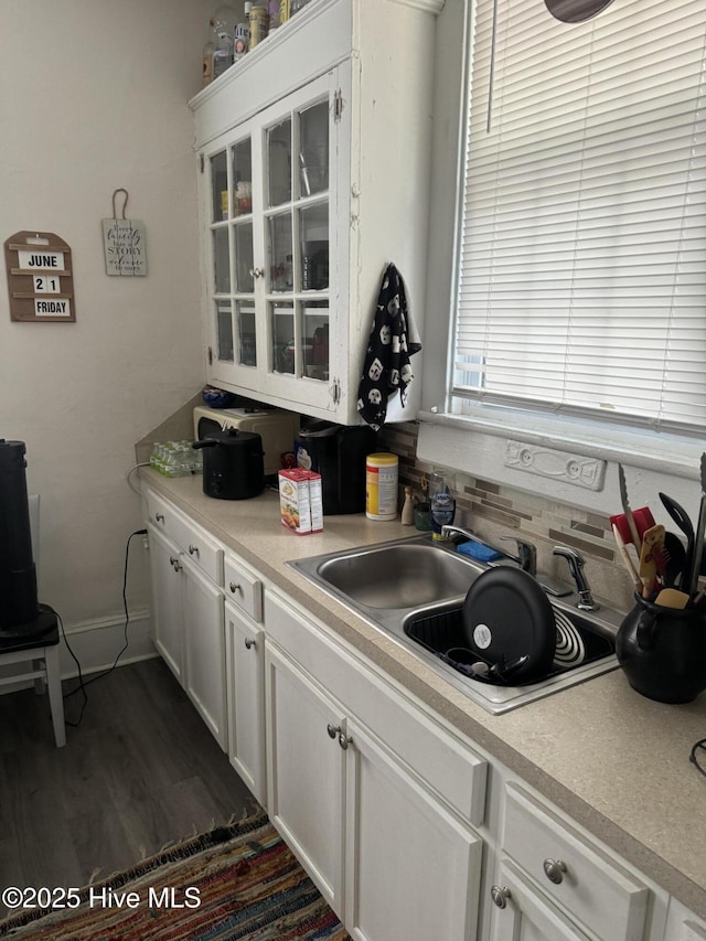 kitchen featuring glass insert cabinets, white cabinets, light countertops, and a sink