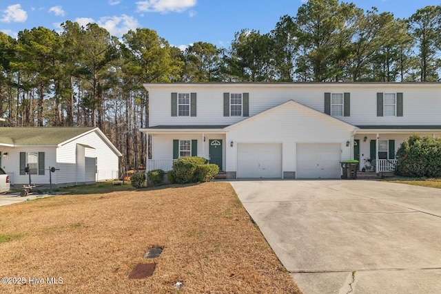 traditional-style house featuring a front yard, covered porch, driveway, and an attached garage