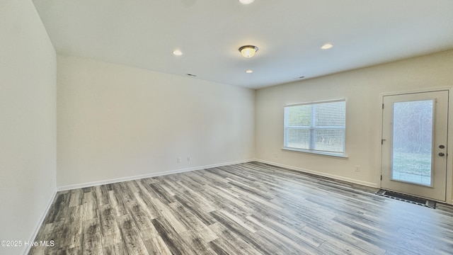 unfurnished room with recessed lighting, wood finished floors, and baseboards