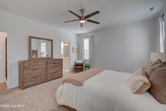 bedroom featuring visible vents, ensuite bathroom, light carpet, ceiling fan, and baseboards