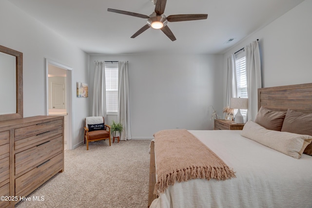 bedroom with light colored carpet, a ceiling fan, baseboards, visible vents, and ensuite bath