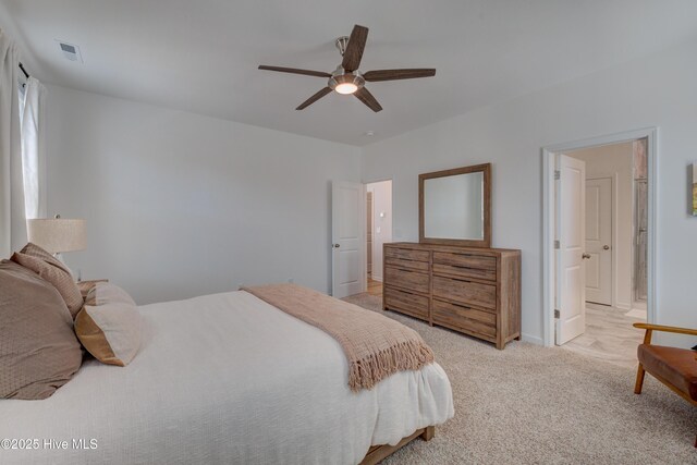 bedroom featuring ensuite bathroom, light colored carpet, a ceiling fan, baseboards, and visible vents