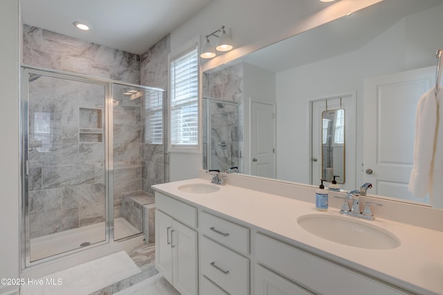 full bathroom featuring double vanity, marble finish floor, a shower stall, and a sink