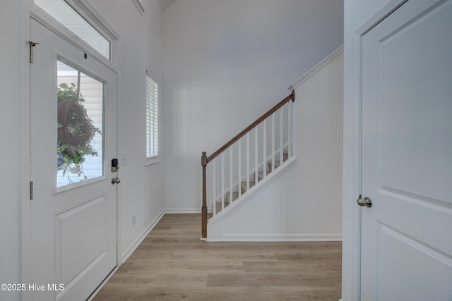 foyer entrance with stairs, light wood-style flooring, and baseboards