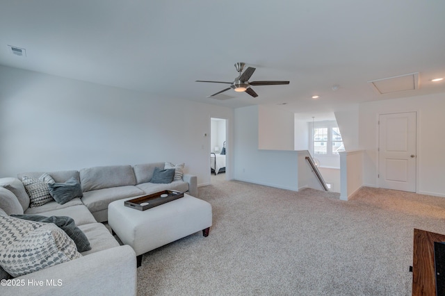 living room with light colored carpet, visible vents, attic access, a ceiling fan, and baseboards