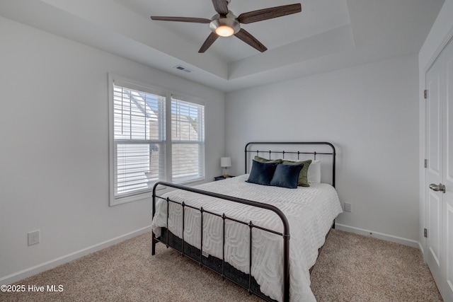 bedroom featuring carpet, a raised ceiling, visible vents, and baseboards