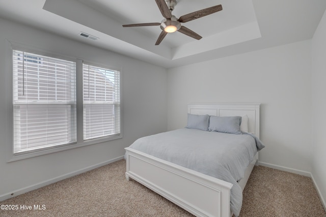 bedroom featuring carpet floors, a raised ceiling, visible vents, a ceiling fan, and baseboards